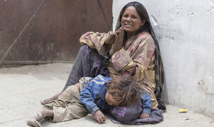 A homeless woman and child sitting on the sidewalk